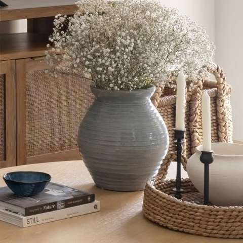 Styled still life with a ceramic vase, dried flowers and woven baskets on a wood console, from a Shan Carlsson Interiors project