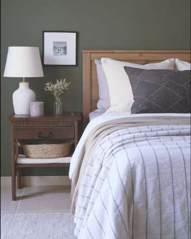 Primary bedroom with olive green walls and a warm wood bed frame, from a Shan Carlsson Interiors project